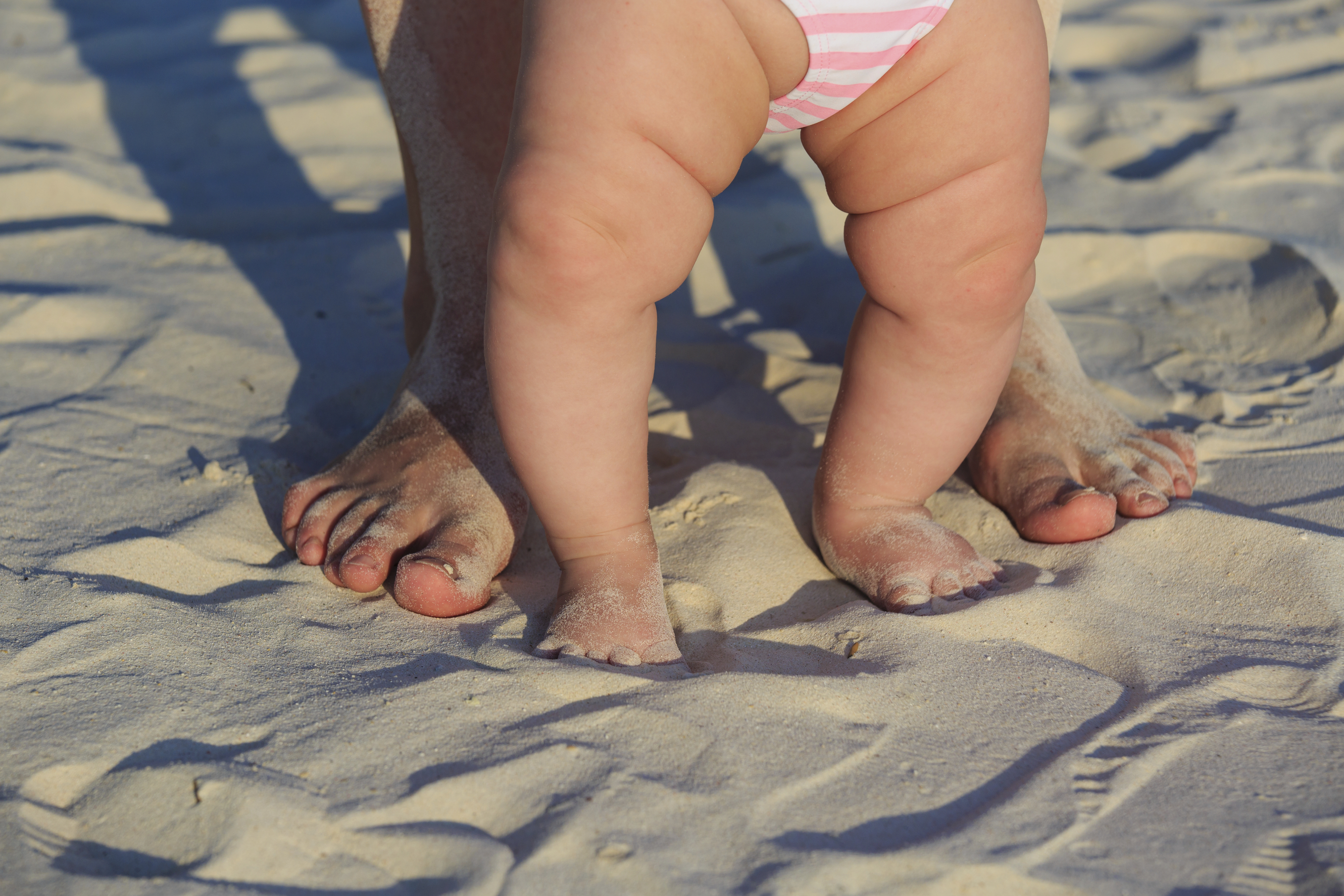 baby and parent feet on sand